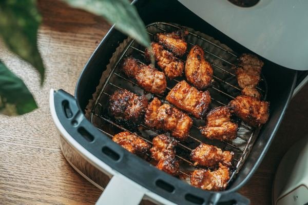 Crispy chicken pieces in an open air fryer basket