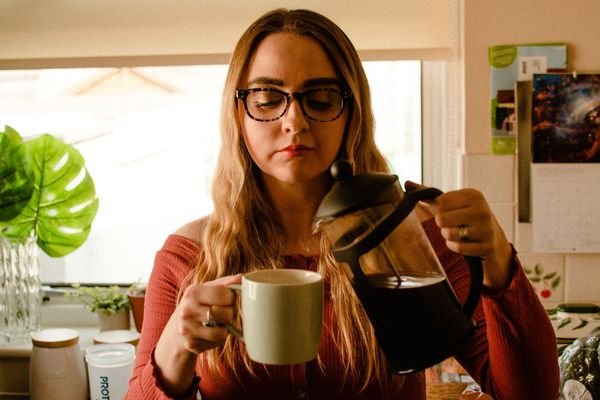 Woman pouring a fresh cup of coffee in a bright kitchen