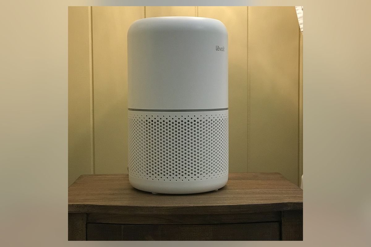 Compact white cylindrical air purifier on a wooden table (representative photo, not the exact product)