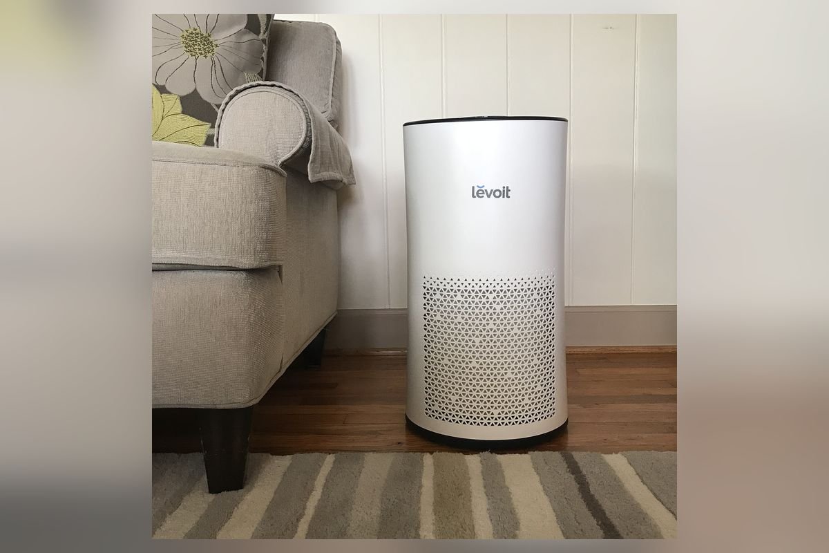 White HEPA air purifier on a rug beside a sofa (representative photo, not the exact product)