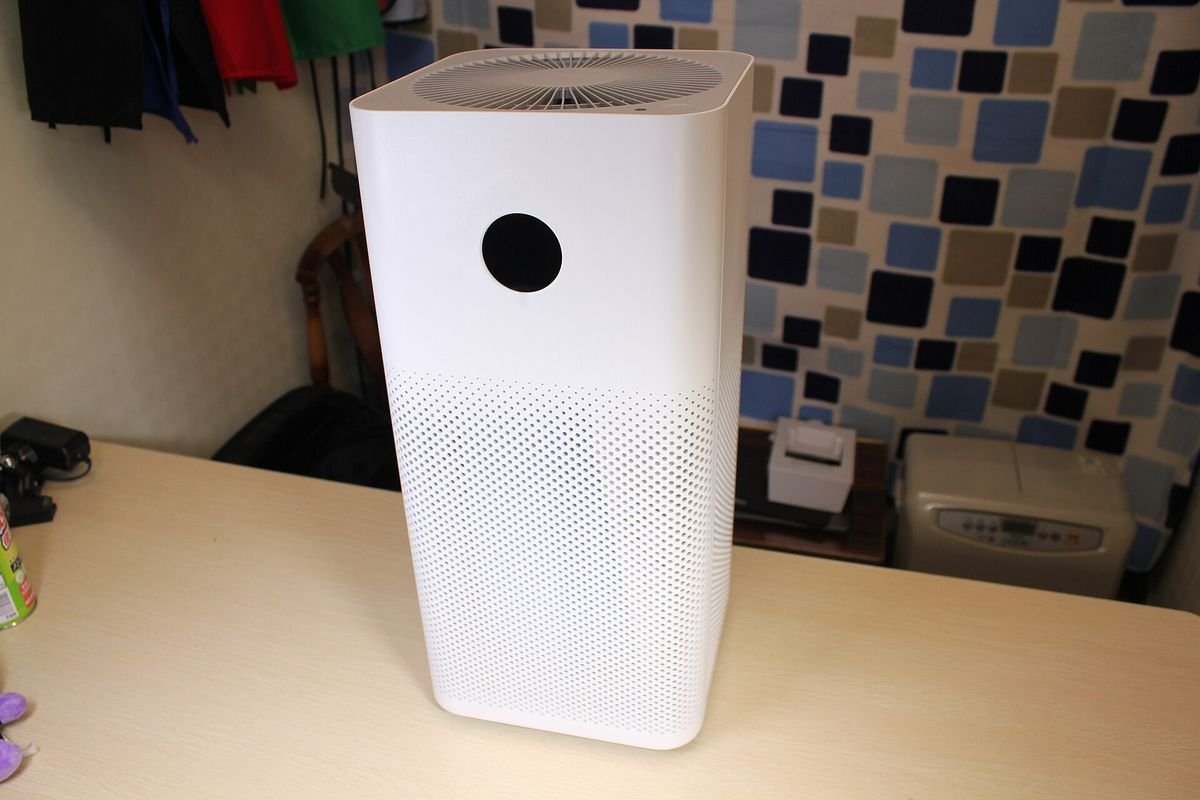 White tower-style smart air purifier on a desk (representative photo, not the exact product)