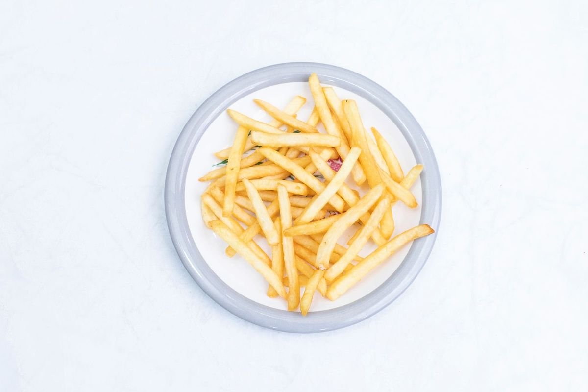 Golden french fries on a white plate, seen from above