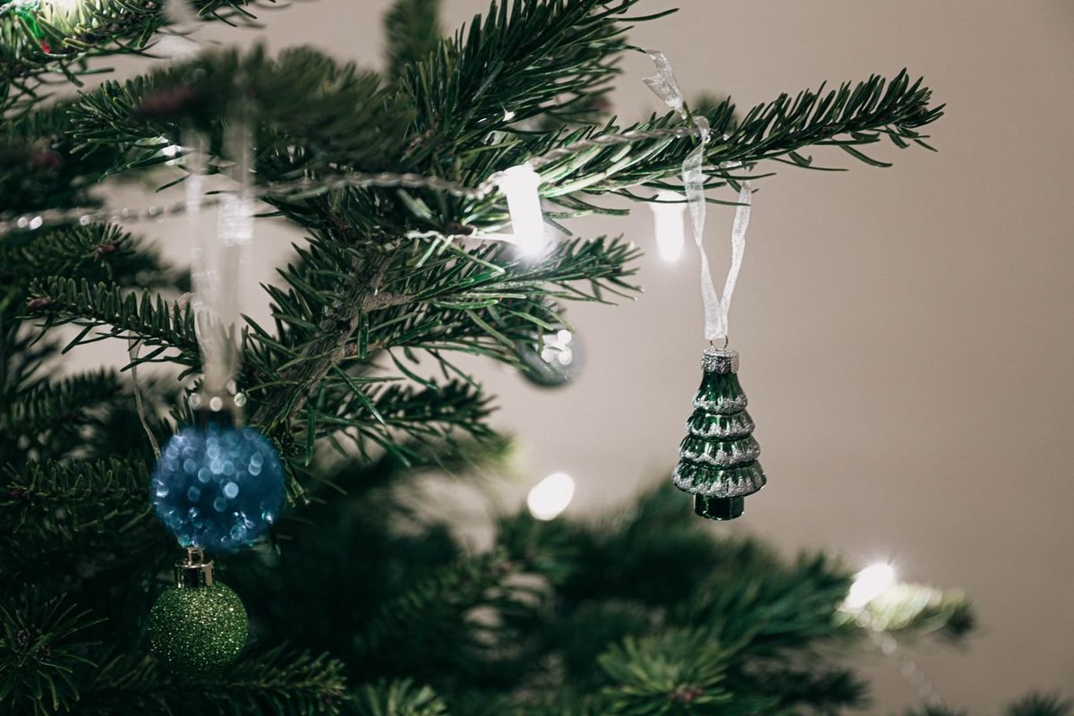 Close-up of realistic evergreen branch tips with blue and glass ornaments and small lights