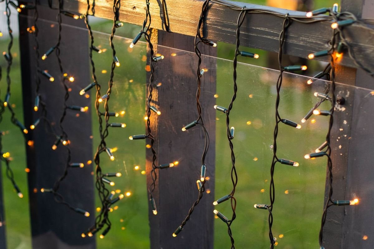 Warm white Christmas string lights draped along a wooden outdoor railing
