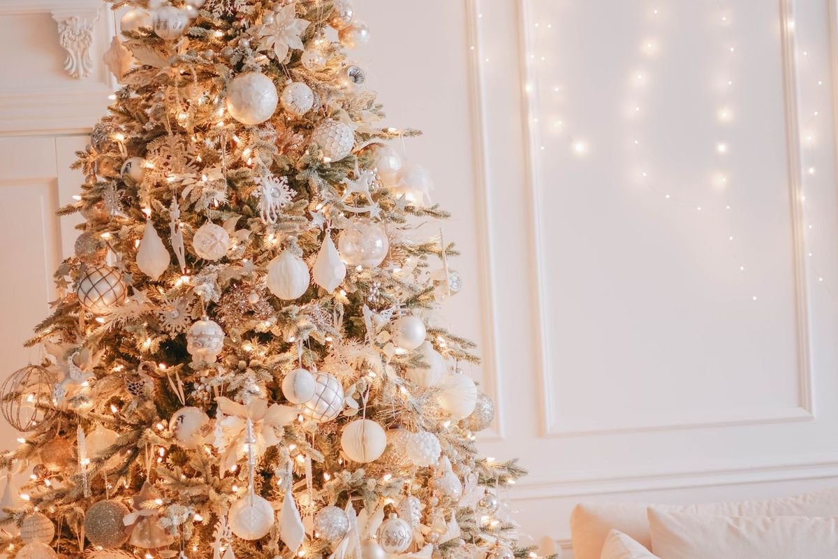 White-flocked Christmas tree glowing with warm white mini lights in a bright white living room (representative photo, not the exact product)