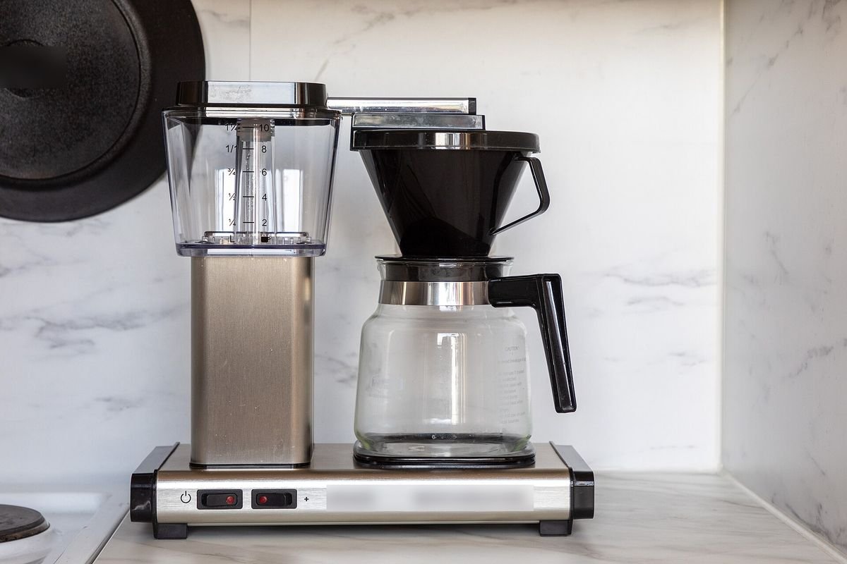 Brushed-silver Moccamaster-style drip coffee maker with a glass carafe on a white marble counter (representative photo, not the exact product)
