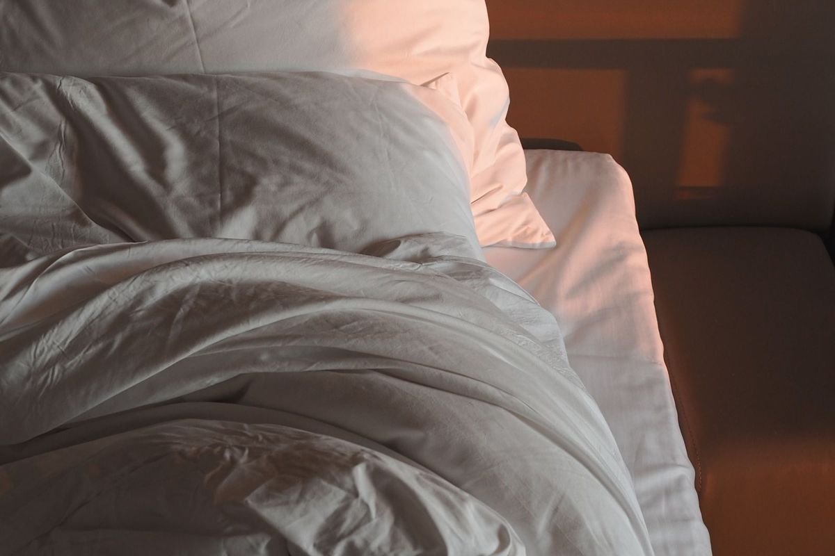 Rumpled white bedding and pillows in warm morning light