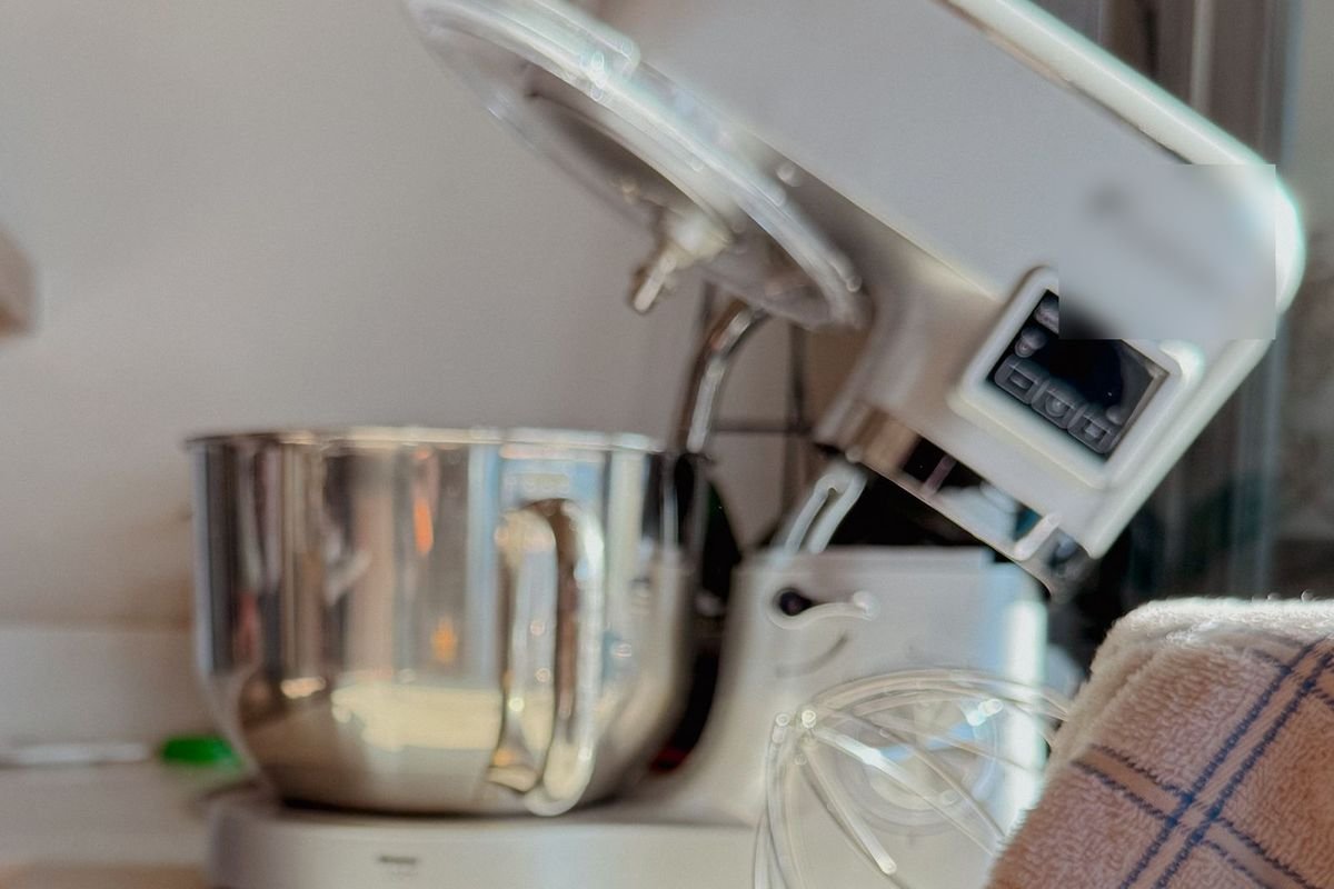 White tilt-head stand mixer with a digital display and stainless bowl in a sunlit kitchen (representative photo, not the exact product)