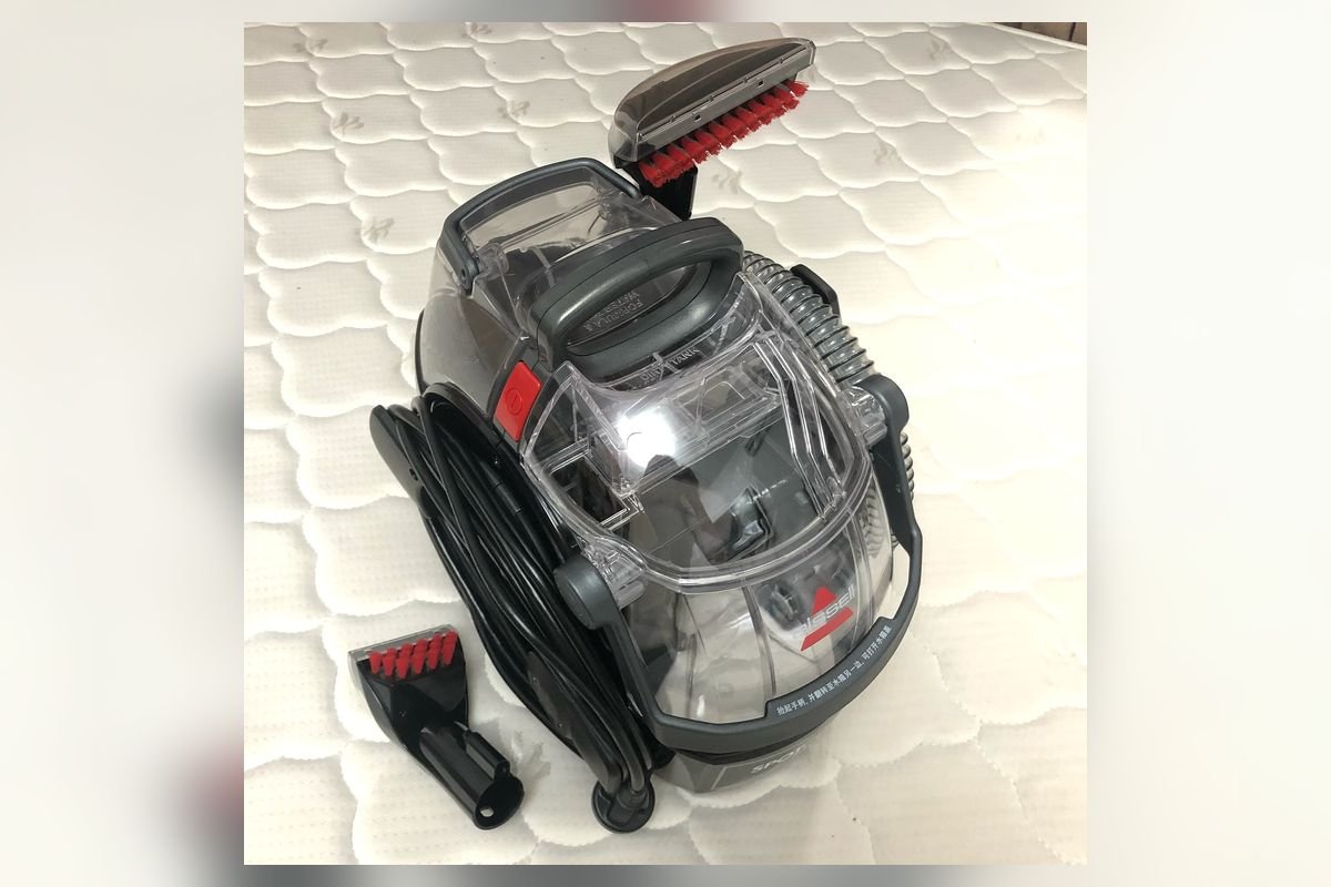 Portable spot carpet cleaner with hose and tool on a white surface (representative photo, not the exact product)
