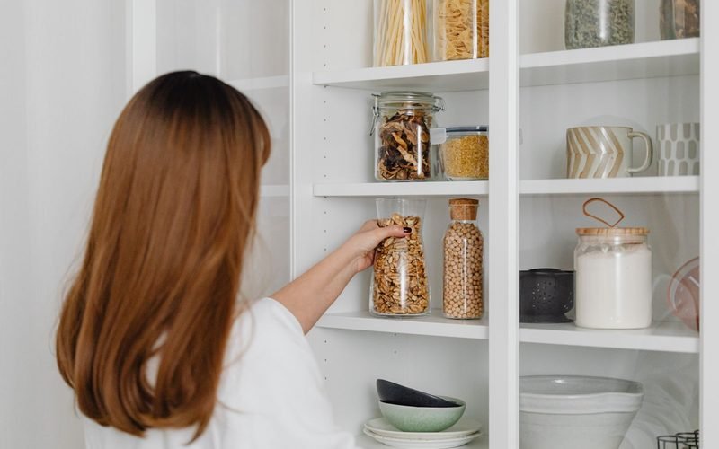 Woman arranging jars on pantry shelves