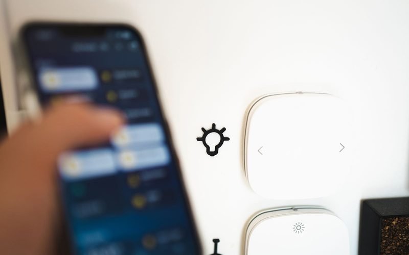 Hand using a smartphone to control smart home devices