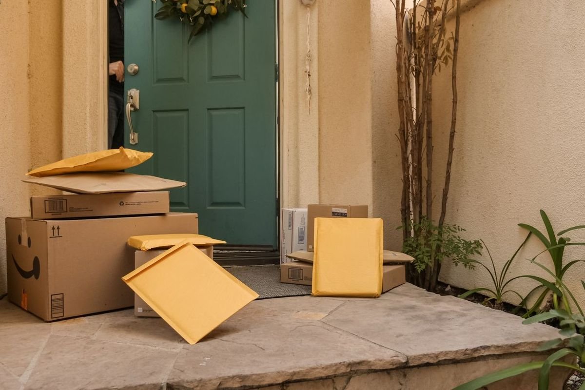 Delivery packages stacked by a teal front door on a porch
