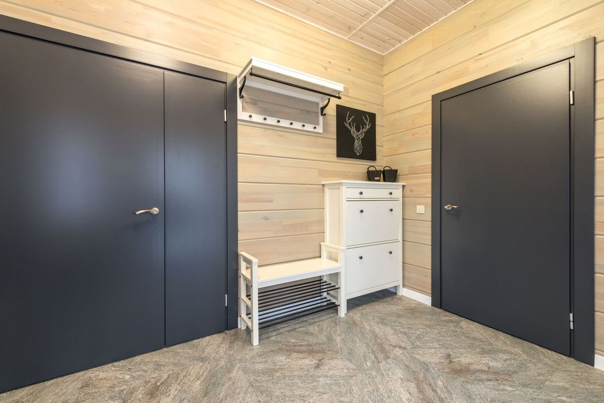 Wood-paneled hallway with a white shoe cabinet, bench and coat hooks (representative photo, not the exact product)