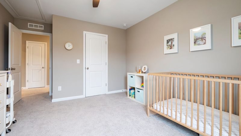 Bright nursery with a light wood crib, cubby shelves, and framed prints