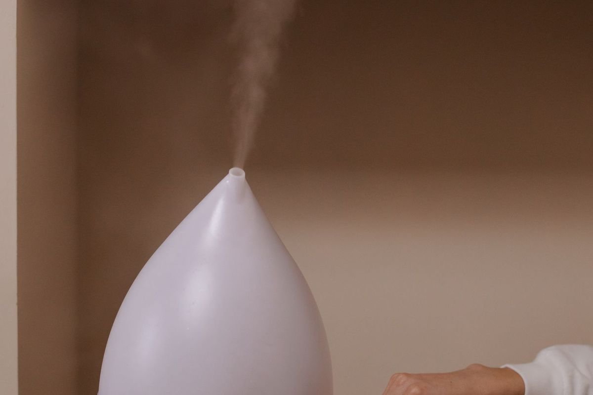 White humidifier releasing cool mist on a wooden stool in a calm, warm-toned room (representative photo, not the exact product)