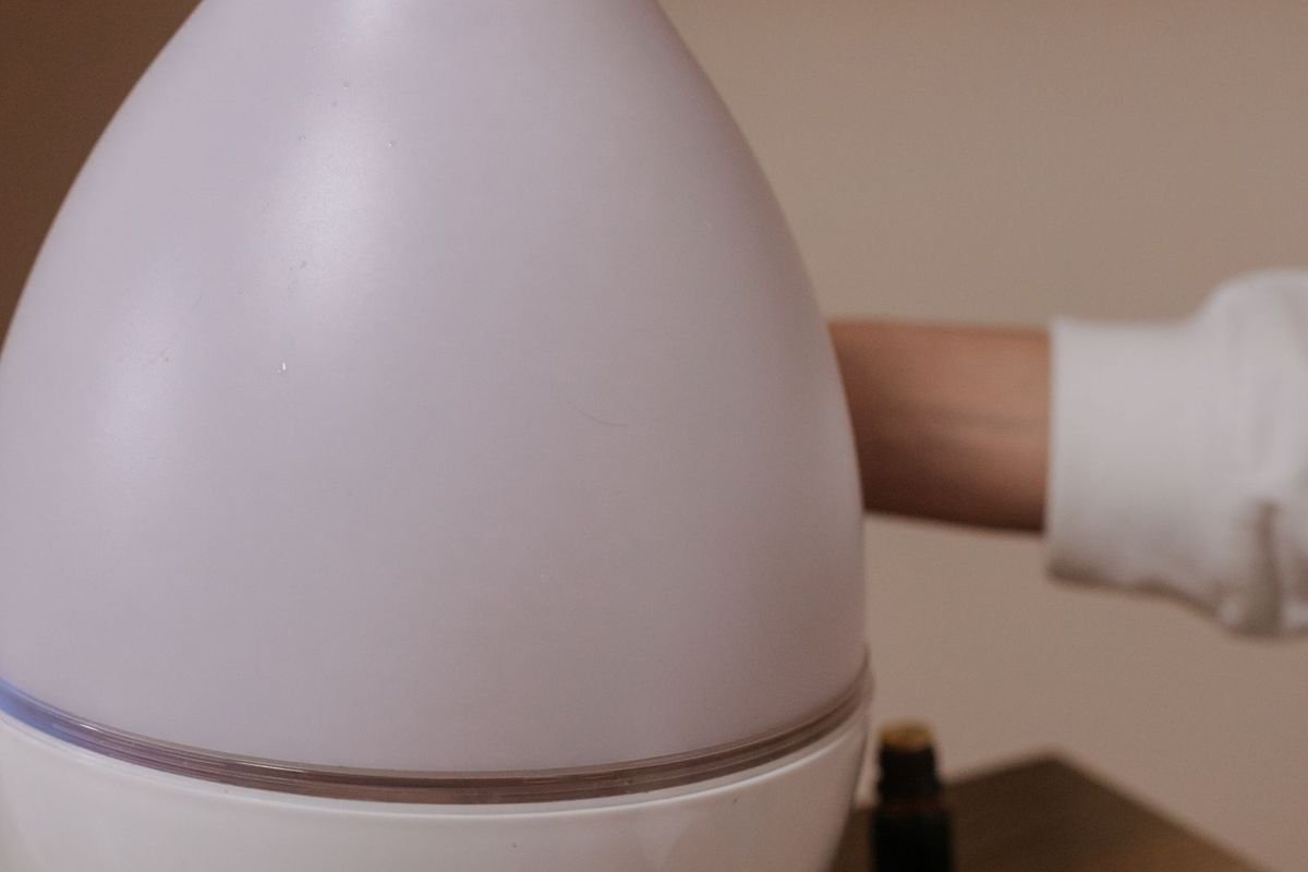 Close-up of a white ultrasonic humidifier emitting a gentle mist on a wooden surface (representative photo, not the exact product)