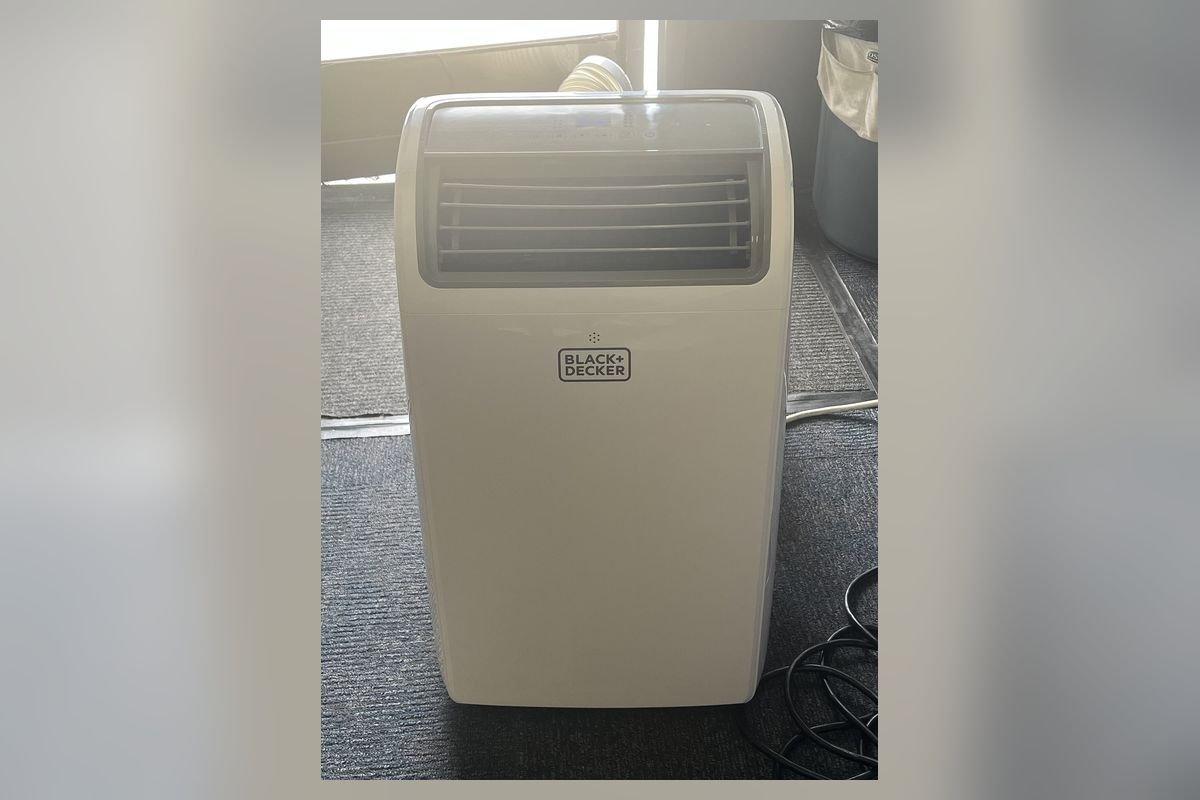 White portable air conditioner on a carpeted floor (representative photo, not the exact product)