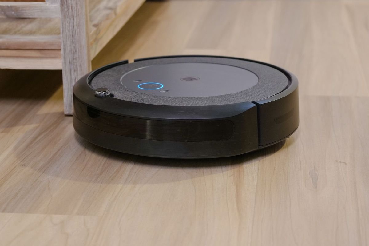 Dark robot vacuum cleaner gliding across a light wooden floor (representative photo, not the exact product)