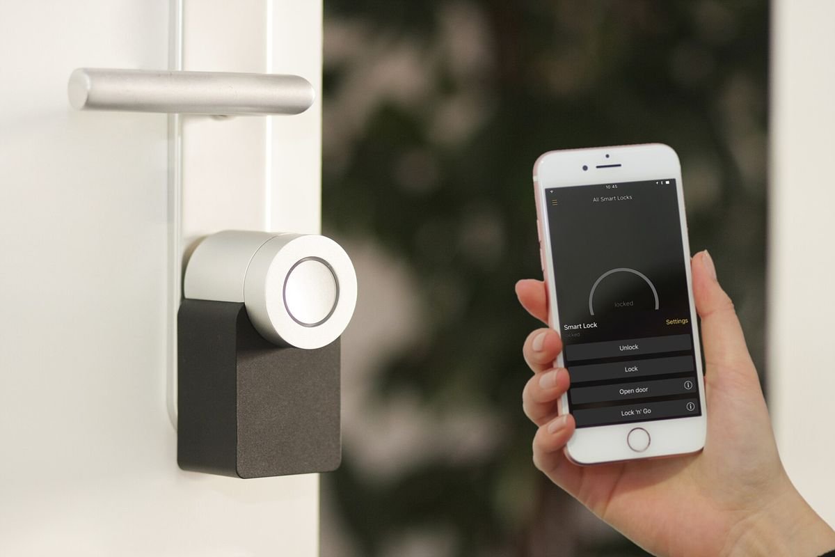 Retrofit smart lock on a door with a phone app in hand (representative photo, not the exact product)
