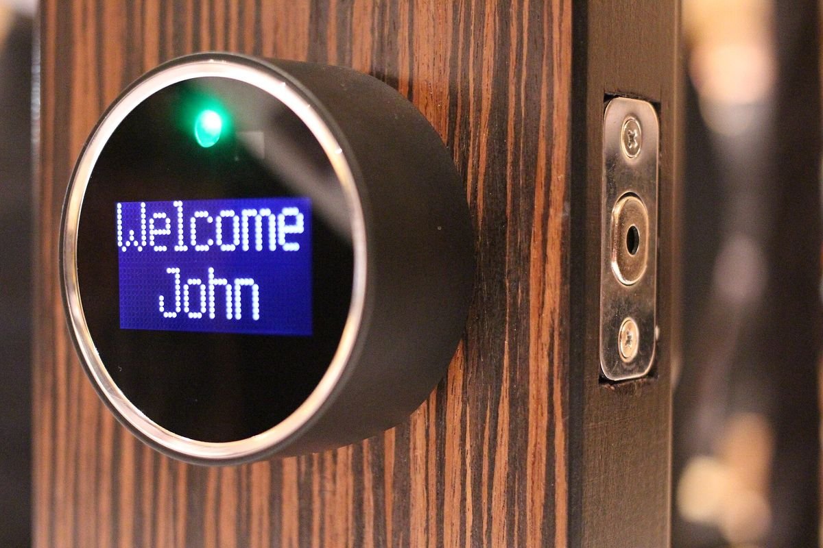 Round smart lock with a lit welcome display on a wooden door (representative photo, not the exact product)
