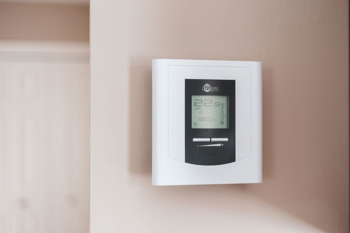 White digital thermostat mounted on a wall (representative photo, not the exact product)