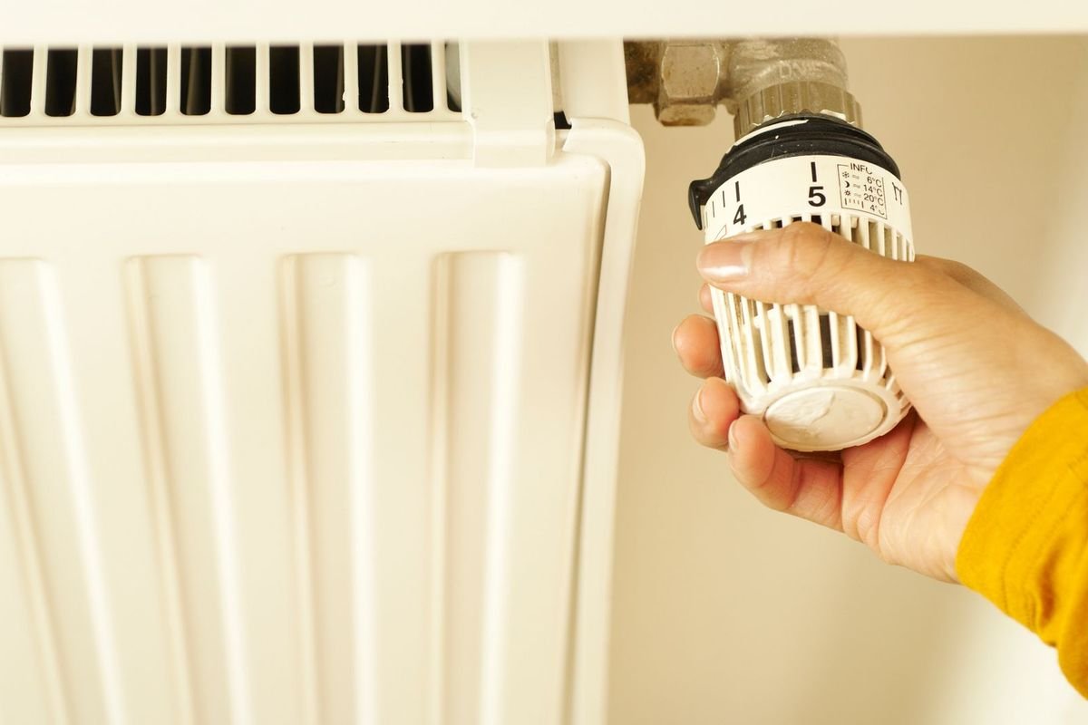 Hand turning a radiator thermostat valve (representative photo, not the exact product)