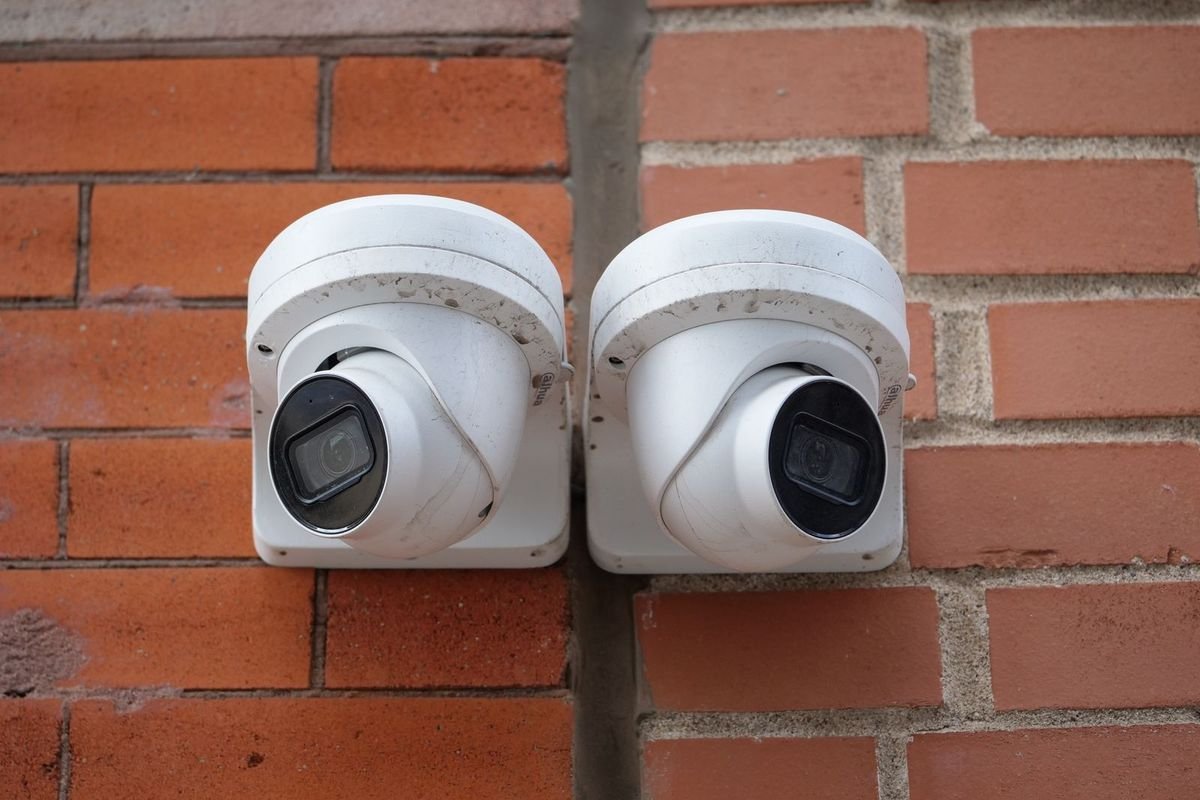 Two white dome security cameras on a brick wall (representative photo, not the exact product)
